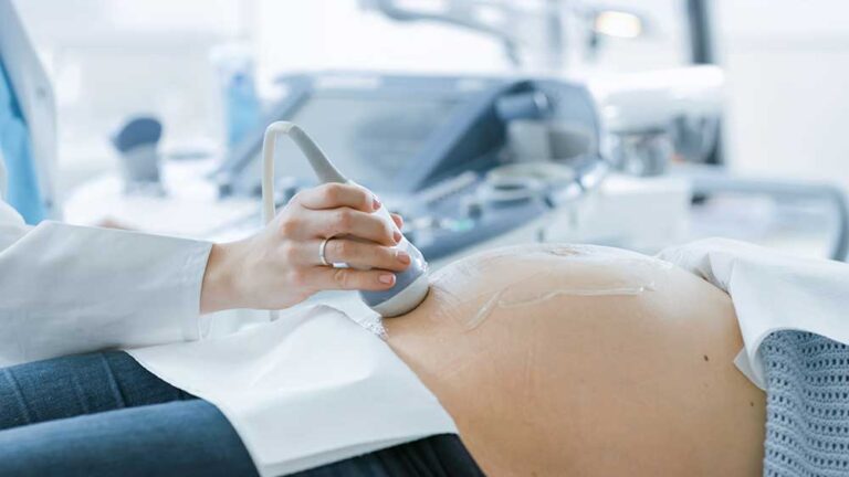 Ultrasound technician performing an abdominal scan on a pregnant woman.